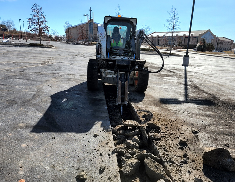 Man in construction machine performing parking lot maintenance